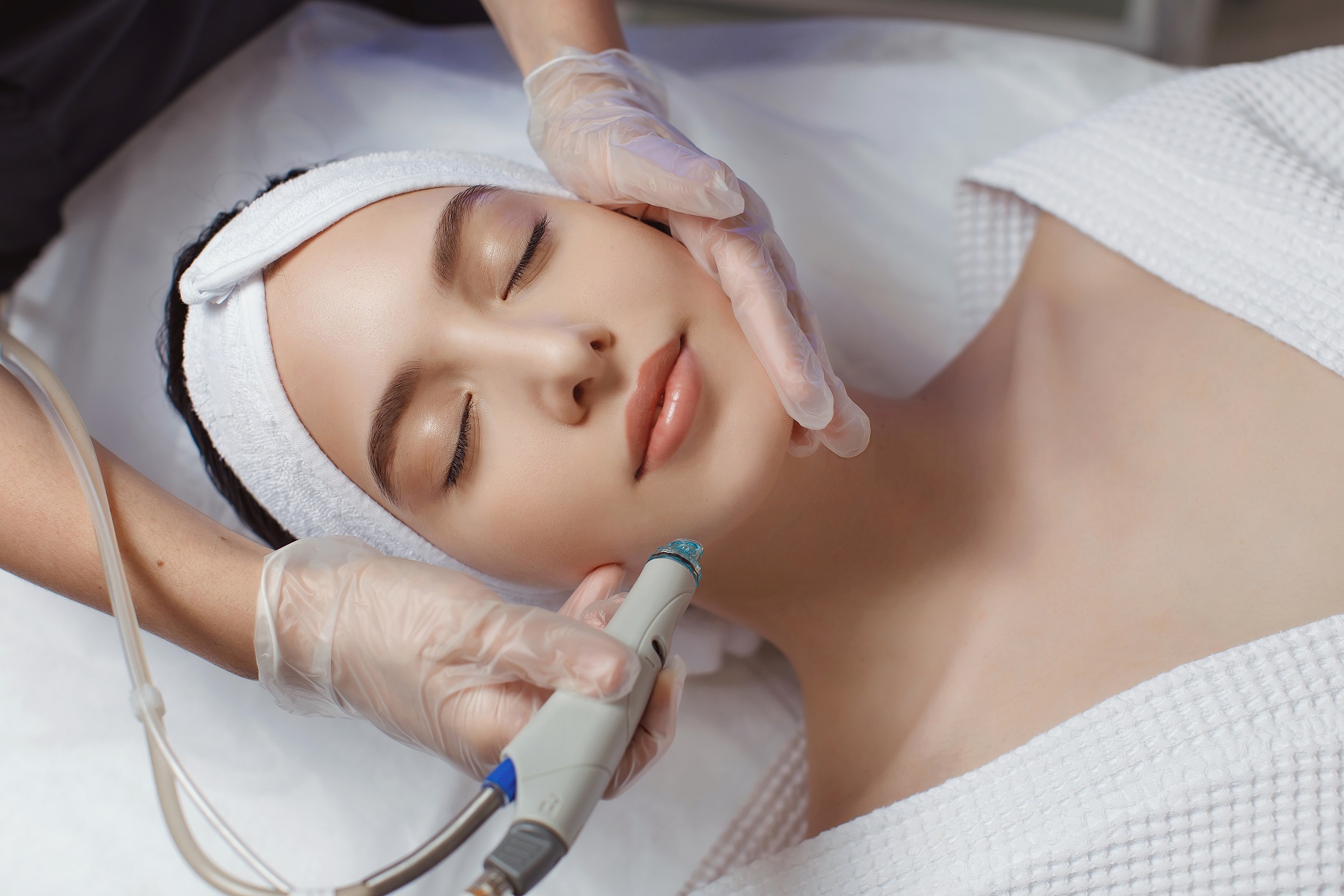 Side view of woman receiving microdermabrasion therapy on forehead at beauty spa. Hydrafacial procedure in Cosmetology clinic.